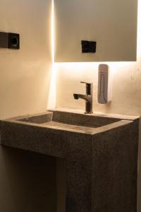 a bathroom sink with a soap dispenser on a wall at The Purple Pineapple Beach Hostel in Kuta Lombok