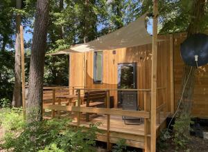 a wooden cabin with a porch and a tent at Tiny House am Ranziger See in Tauche