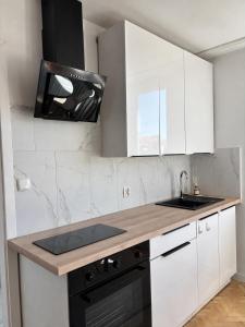 a kitchen with white cabinets and a black stove at Apartament 3 Maja in Brodnica