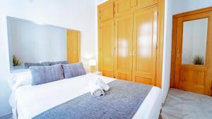 a bedroom with a large white bed with blue pillows at Bonito y acogedor apartamento pleno centro junto Catedral in Granada
