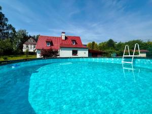 a house with a red roof and a large swimming pool at Domeček Drahuška - own fishing in Janov