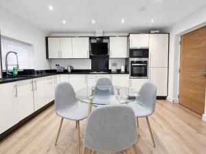 a kitchen with a glass table and four chairs at Relax in a Spacious 2-Bed Pinner Hideaway in Northwood