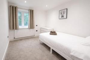 a white bedroom with a bed and a window at Relax in a Spacious 2-Bed Pinner Hideaway in Northwood +3 photos