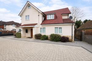 a white house with a red roof on a driveway at Relax in a Spacious 2-Bed Pinner Hideaway in Northwood