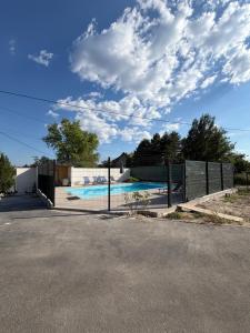 a fence with a swimming pool behind it at Maison plein-pied 8 pers avec piscine sur demande in Thiers