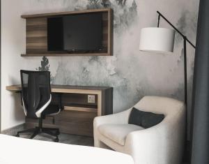 ein Wohnzimmer mit Fernseher, Sessel und Schreibtisch in der Unterkunft Hotelia in Saint-Ambroise