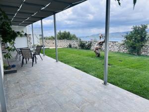 a patio with a table and chairs on the grass at Argo Summer Apartment in Agioi Apostoli