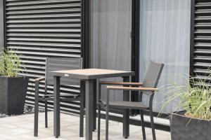 Ein Tisch und Stühle auf einer Terrasse mit Pflanzen in der Unterkunft Hotelia in Saint-Ambroise