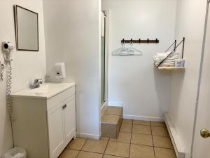 a white bathroom with a sink and a mirror at Auberge Maison Gauthier in Tadoussac +56 photos