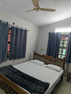 a bedroom with a bed with blue curtains and a ceiling fan at Coorg homes in Madikeri