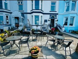 a patio with tables and chairs in front of a building at Hotel No5, Beachfront with Free Private Car Park in Llandudno