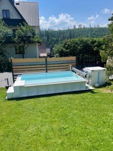 a large swimming pool in a yard with a bench at Domki Chatka U Staszka in Małe Ciche