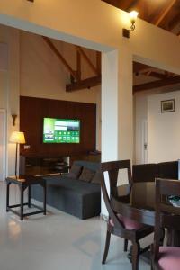 a living room with a couch and a tv on a wall at Wisteria Cottage in Dunga Gali