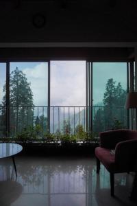 a room with a large window and a couch and a table at Wisteria Cottage in Dunga Gali