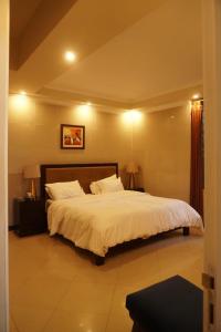 a bedroom with a large white bed with two lamps at Wisteria Cottage in Dunga Gali
