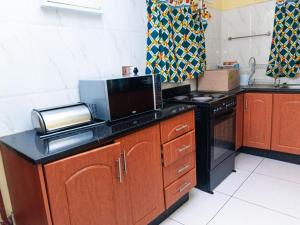 a kitchen with a stove and a microwave at JAC Tilama BNB in Blantyre