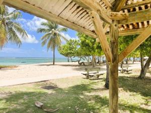 a wooden pergola on a beach with a picnic table at Le Cocon Bleu in Le Moule