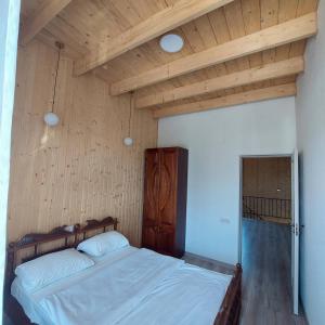 a bed in a room with a wooden ceiling at Spitak tun in Ijevan