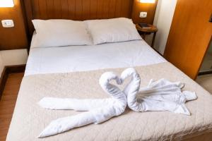 a bed with two towels in the shape of hearts at HANNA Pórtico Hotel - Gramado in Gramado