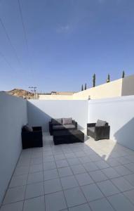 a white wall with two couches on a patio at شقة ريفالا الفاخرة in Abha