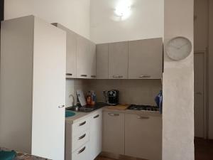 a kitchen with white cabinets and a clock on the wall at Tropea's green terrace in Tropea