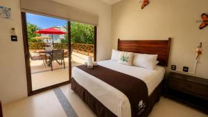 a bedroom with a bed and a balcony with a table at Villas Palmar Holbox in Holbox Island +127 photos