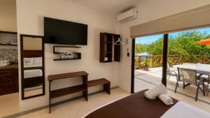 a living room with a television and a balcony at Villas Palmar Holbox in Holbox Island