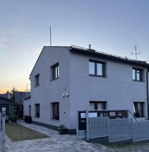 a white house with a fence in front of it at Penzion Cohla - Nová Paka in Nová Paka
