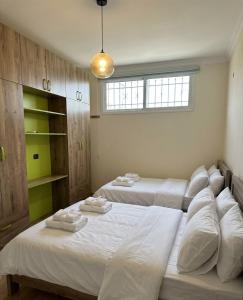 a bedroom with two beds with white sheets and a window at Berbara, Chadi in Dayr Jannīn