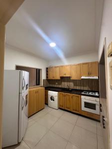 a kitchen with wooden cabinets and a white refrigerator at Berbara, Chadi in Dayr Jannīn +4 photos