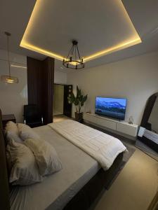 a bedroom with a large bed with a tv on the wall at Jasabi Apartments in Port Harcourt