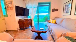 a living room with a couch and a tv and a table at Aurora Maris Maisonette in Possidi