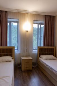 two beds in a room with two windows at Spitak tun in Ijevan +8 photos