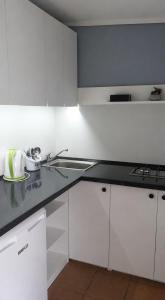 a kitchen with white cabinets and a black counter top at Domki Bliźniak in Ustka +8 photos