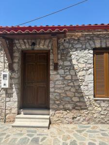 a stone house with a wooden door and two windows at Stone house Amfikleia in Amfikleia