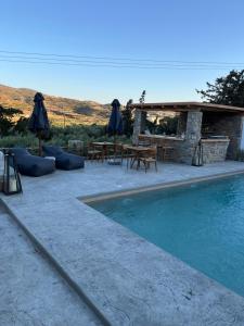 a swimming pool with tables and umbrellas next to a patio at Ninemia Naxos Suites in Naxos Chora