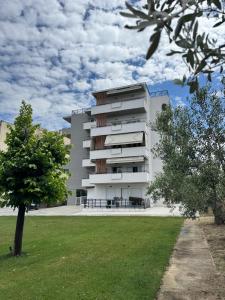 a white building with a tree in front of it at Covea by the Sea Boho Seaside Apartment, 400 m from the Beach in Perea
