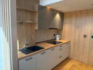 a kitchen with white cabinets and a sink at Biała Stodoła in Płoskie +4 photos