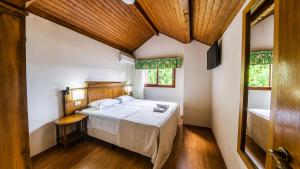 a bedroom with a bed and two windows at HANNA Pórtico Hotel - Gramado in Gramado