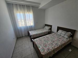 two beds in a small room with a window at Appartement 3 chambres bien situé à Mrezga in Hammamet Nord