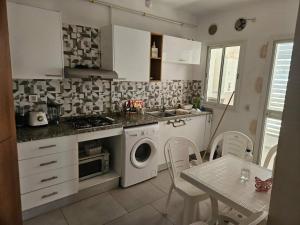 a kitchen with a washing machine and a table with chairs at Appartement 3 chambres bien situé à Mrezga in Hammamet Nord +6 photos