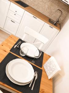 a kitchen table with white plates and utensils on it at Cinque Terre Sweet Home - Centro La Spezia - 5 min stazione - Ideale Cinque Terre - WiFi e AC in La Spezia