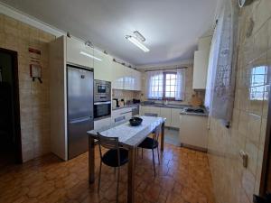 a kitchen with a table with chairs and a refrigerator at Sitio dos Machados in Póvoa de Lanhoso