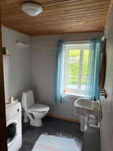 a bathroom with a toilet and a sink and a window at Skjellfjord cabin in Skjelfjord +12 photos