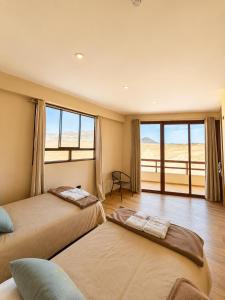 two beds in a room with a large window at Family Surf Chicama in Puerto Chicama