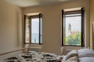 a bedroom with a bed and two windows with a tower at Castravalva Villa by Rent All Como in Mezzegra