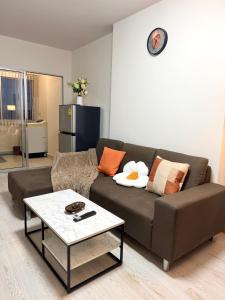 a living room with a brown couch and a table at Breezy 1BR Near BTS Udomsuk in Amphoe Phra Khanong