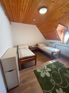 a attic room with two beds and a rug at Családfa Vendégház in Ságvár
