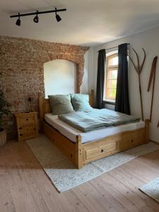 a bedroom with a wooden bed and a brick wall at falternhof apartment - geschichte trifft auf design in Höslwang