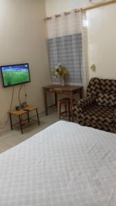 a room with a bed and a couch and a television at EHBC Loc in Tambacounda